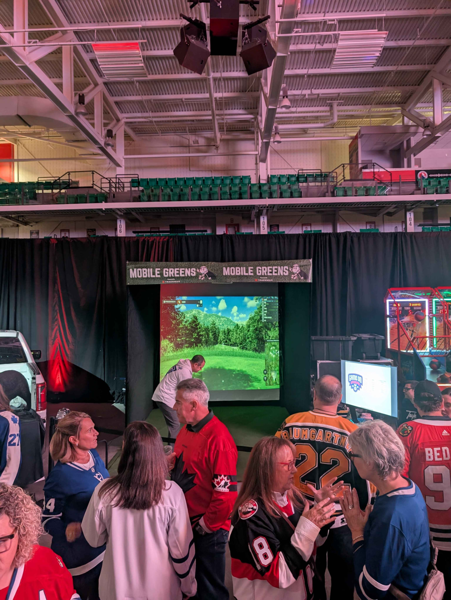Mobile Greens simulator bay at an indoor arena fan event with hockey fans