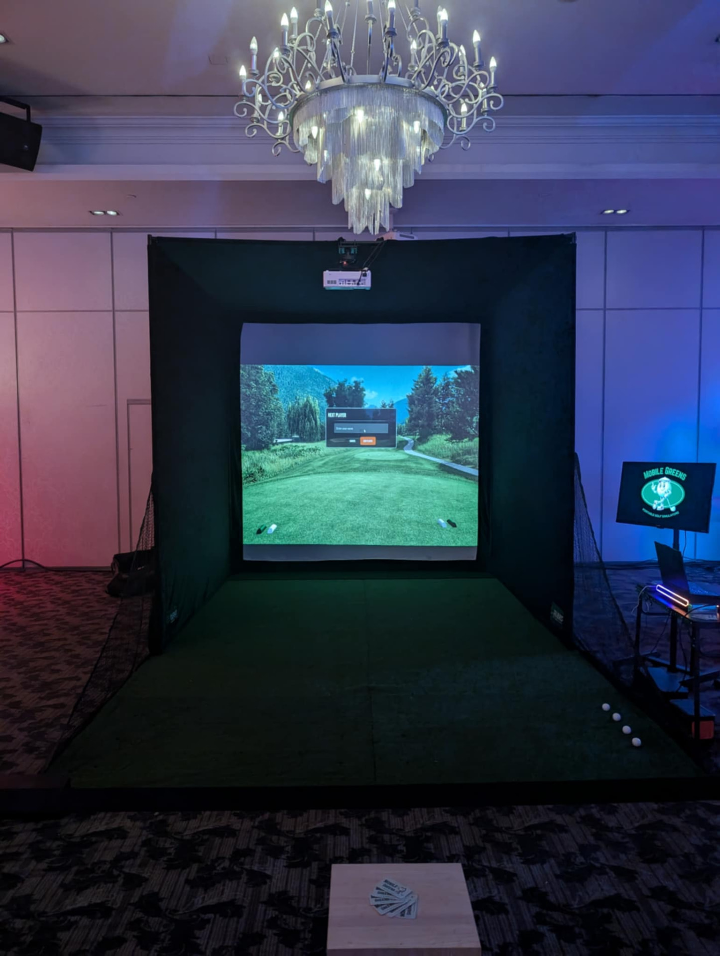 Indoor full simulator rental with uplighting under a ballroom chandelier